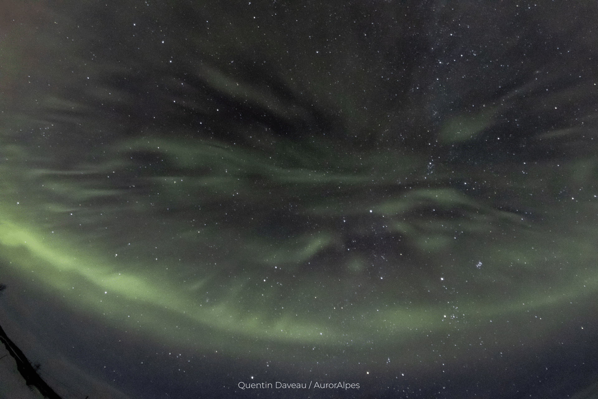 Des aurores pulsantes, à proximité de Kilpisjärvi (Finlande). Le contraste a été augmenté pour mieux voir les structures. En bas de l'image, un arc auroral plus intense se dessine.