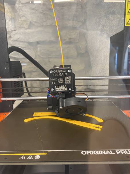 Une tête d'impression d'imprimante 3D qui imprime deux branches jaunes.